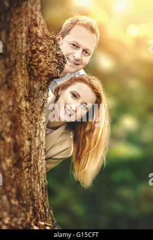 Happy young couple standing behind tree et d'avoir du plaisir Banque D'Images