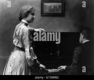 Keller debout à piano, dont l'homme est à l'affiche, vers 1904. Helen Adams Keller (27 juin 1880 - 1 juin 1968) était un écrivain, activiste politique, et conférencier. Elle avait 19 mois quand elle a contracté une maladie, qui pourrait avoir été scarlet fev Banque D'Images