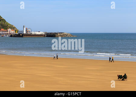 Diverses personnes sur la plage. Deux personnes assis dans des chaises. à Scarborough, Angleterre. Banque D'Images