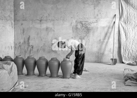 Fazl Abol, Potter's assistant, avec des pots d'argile faites par Iradj Naderi dans son atelier de Lalejin, Hamadan, Province de l'Iran. Banque D'Images