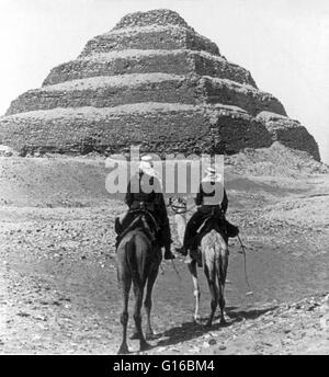 Intitulé : "soldats Nubiens riding camel col la Pyramide, Désert de Libye, l'Égypte'. La pyramide de Djoser (ou Zoser), ou pyramide (kbhw-ntrw en égyptien) est un site archéologique restent dans la nécropole de Saqqara, Egypte, au nord-ouest de la ville de Memphis. Banque D'Images