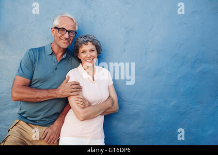 Portrait of happy senior homme et femme ensemble contre fond bleu. Couple d'âge moyen à la caméra et au sourire avec c Banque D'Images