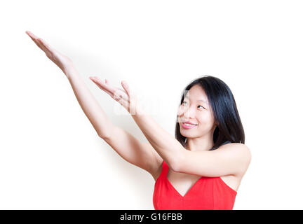 Belle jeune femme asiatique en robe rouge souriant et soulignant isolé sur fond blanc portrait Banque D'Images