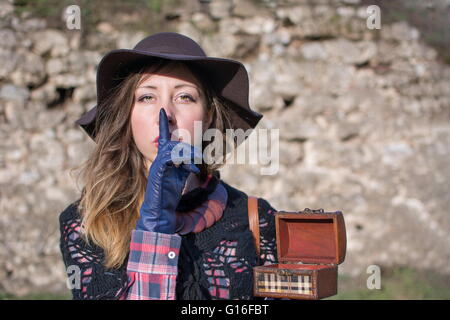 Mystérieuse Jeune femme tenant une vieille boîte en bois à l'extérieur et exigeant le silence. Chut ! Banque D'Images