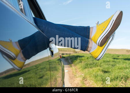 Femme jambes hors de la fenêtre de voiture. Billet et fun Banque D'Images