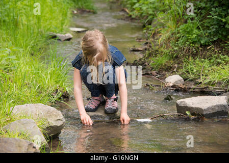 Cute little girl having fun par une rivière sur jour d'été chaud et ensoleillé Banque D'Images