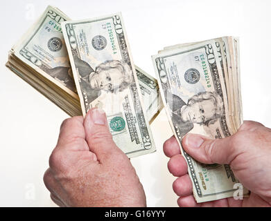 Older Man's hands comptant vingt dollars dans une pile sur fond blanc Banque D'Images