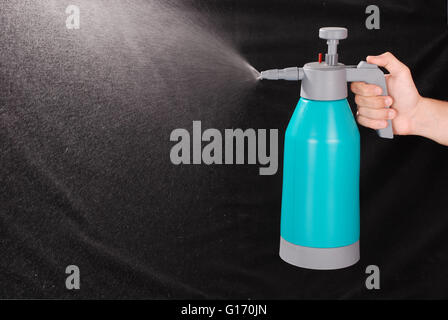 Male hand holding spray bottle isolé sur fond noir Banque D'Images