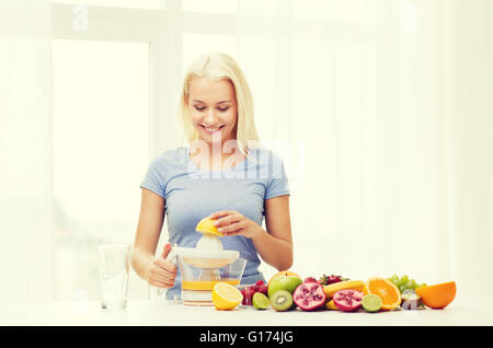 Smiling woman squeezing jus de fruit à la maison Banque D'Images