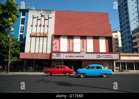 Deux vieilles voitures américaines des années 1950 après que la révolution passe devant un cinéma art déco bâtiment dans Vedado La Havane Cuba Banque D'Images