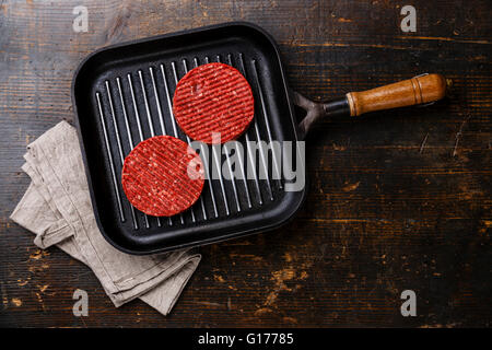 Burger de viande de boeuf haché cru escalopes steak sur poêlon sur fond de bois Banque D'Images