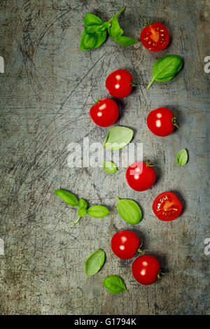 Les tomates cerise avec des feuilles de basilic sur fond rustique Banque D'Images