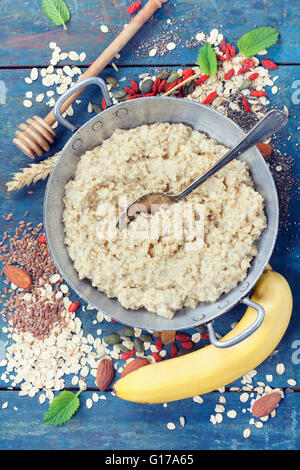 Petit déjeuner sain. L'avoine fait maison du porridge, les baies de goji, banane, potiron et chia graines dans un bol en métal sur ba rustique en bois Banque D'Images