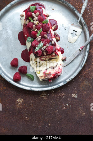 Semifreddo fromage italien ou entremets glacé aux pistaches, framboises et menthe sur vintage silver tray sur rusty gru Banque D'Images