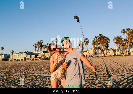 Couple avec smartphone selfies stick on beach, Venice Beach, California, USA Banque D'Images