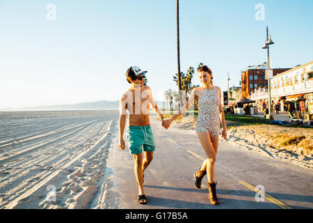 Jeune couple portant un maillot et short en flânant au beach, Venice Beach, California, USA Banque D'Images