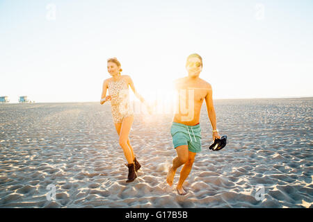 Jeune couple portant un maillot et short d'exécution sur la plage ensoleillée, Venice Beach, California, USA Banque D'Images