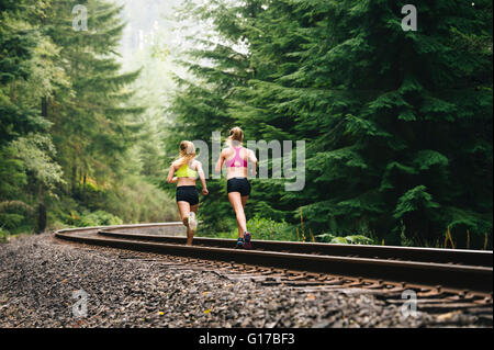 Jeune femme et adolescente le long d'une voie de chemin de fer en milieu rural, vue arrière Banque D'Images