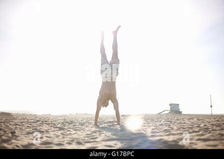 Mid adult man doing handstand on beach Banque D'Images