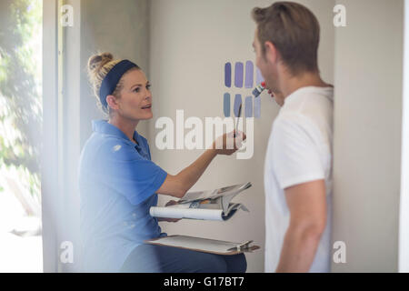 Couple holding brochure présentant des couleurs de peinture sur mur Banque D'Images