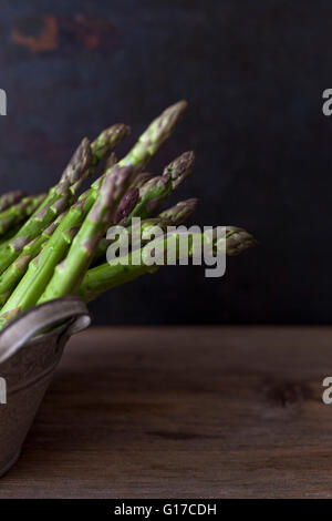 Les asperges vertes fraîches dans un vieux seau sur une table en bois rustique Banque D'Images