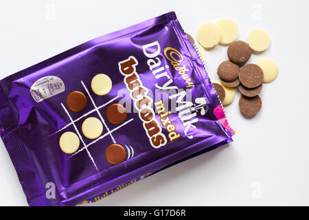 Sac de lait Cadbury chocolats boutons mixte ouvert et s'échappe au contenu ensemble renversé sur fond blanc Banque D'Images