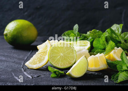 Tranches de Lime et de citrons avec bouquet de menthe fraîche sur l'ardoise noire sur fond texturé noir Banque D'Images