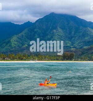 La kayakiste dans la baie de Hanalei au coucher du soleil voit waterfall Banque D'Images