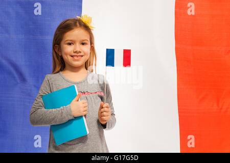 Fille avec un drapeau et livre contre bannière française Banque D'Images