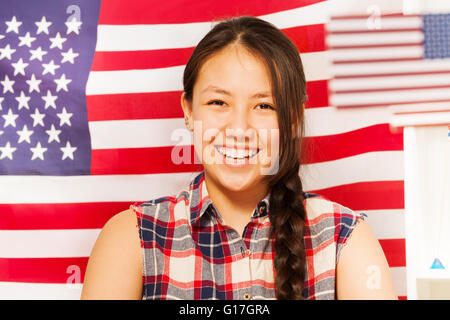 Smiling teenage girl avec le drapeau américain derrière elle Banque D'Images