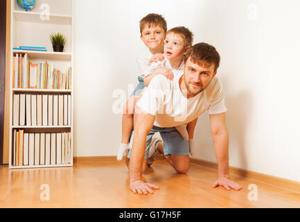 Père donnant à ses deux fils piggy back ride Banque D'Images