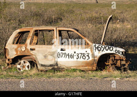 For sale sign humoristique peint sur voiture abandonnée sur le bas-côté de la route dans l'ouest du Texas. Banque D'Images