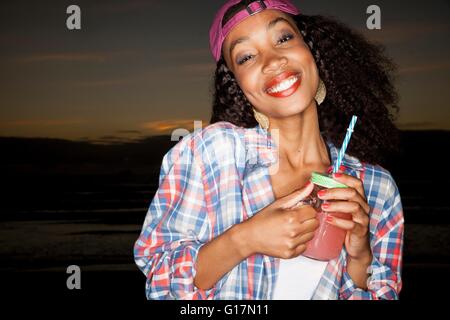 Jeune femme portant casquette à l'envers holding pot Mason smiling at camera Banque D'Images