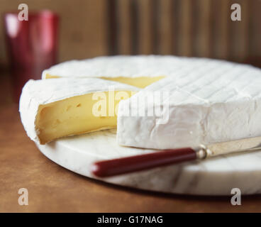 Brie rond avec couteau à fromage sur une planche à découper en marbre Banque D'Images