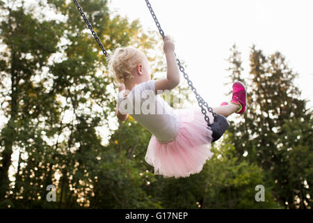 Baby Girl swinging sur park swing, vue arrière Banque D'Images