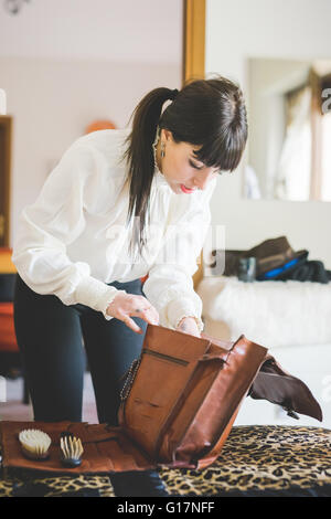 Jeune femme sac de remplissage dans la chambre Banque D'Images