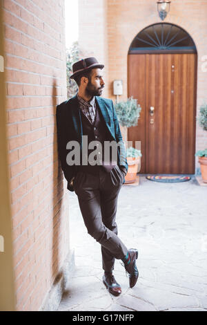 Young man leaning against brick wall Banque D'Images