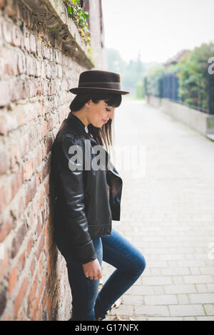 Young woman leaning against brick wall Banque D'Images