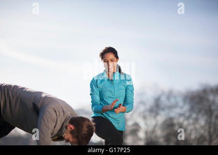 Young woman clapping man doing push up training in park Banque D'Images