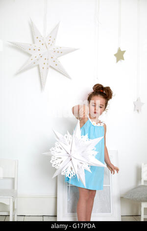 Fille avec coupe-papier star contre mur blanc avec des étoiles Banque D'Images