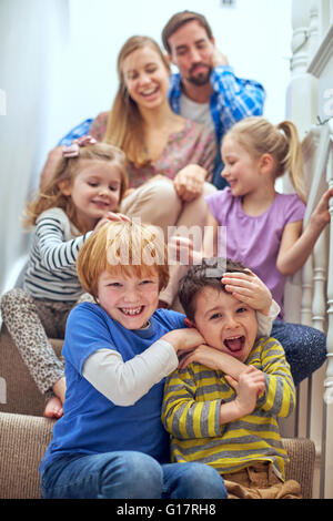 Heureux parents et enfants assis on staircase Banque D'Images