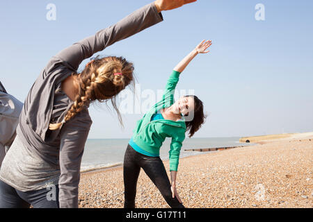 Deux femmes faire réchauffer la formation, plier latéralement sur la plage de Brighton Banque D'Images