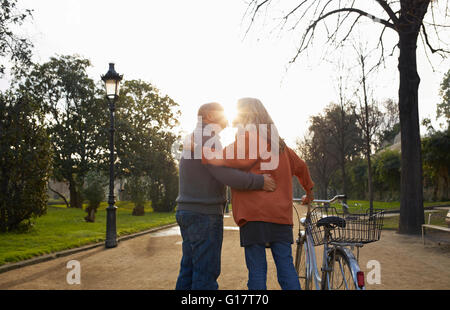 Couple on chemin bordé d'arbres holding location kissing Banque D'Images