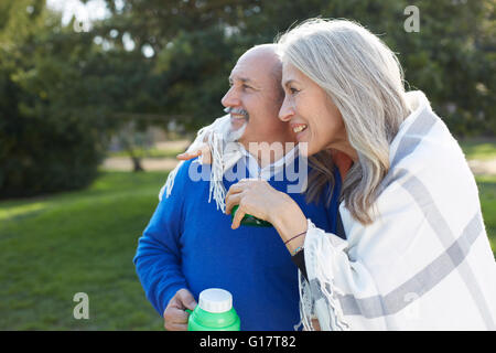 Couple blanket holding drinks jaugée à l'écart smiling Banque D'Images