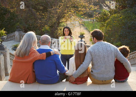 Mid adult woman using smartphone pour prendre des photo de famille dans park Banque D'Images