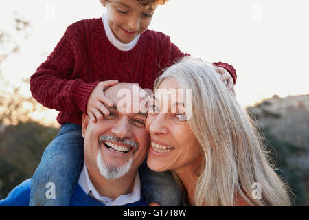 Les grands-parents avec petit-fils sur les épaules à la caméra en souriant Banque D'Images