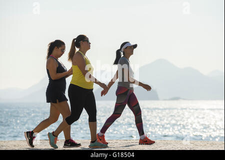 RIO DE JANEIRO - le 3 avril 2016 : un trio de marcheurs fitness pass le long d'un matin lumineux vue sur la promenade de Copacabana. Banque D'Images