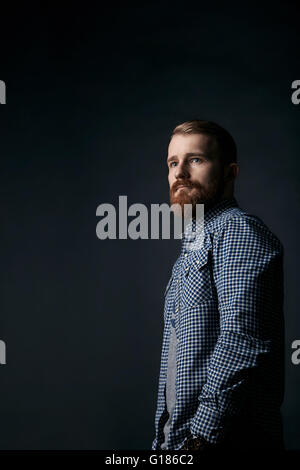 Homme barbu rouge pensive portrait studio sur fond sombre Banque D'Images