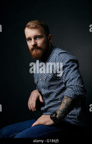 Homme barbu rouge réfléchie studio portrait sur fond sombre Banque D'Images