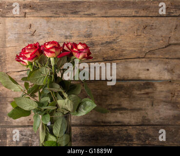 Bouquet de roses rouges dans un vase sur fond de bois with copy space Banque D'Images